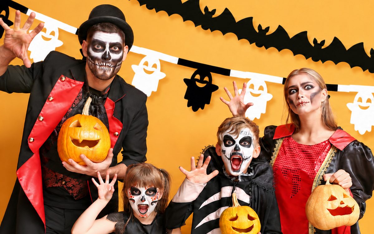 Charakteryzacja na Halloween — dorośli w strojach wampira i wampirzycy oraz dzieci jako kościotrupy, z makijażem czaszki i dyniami w rękach