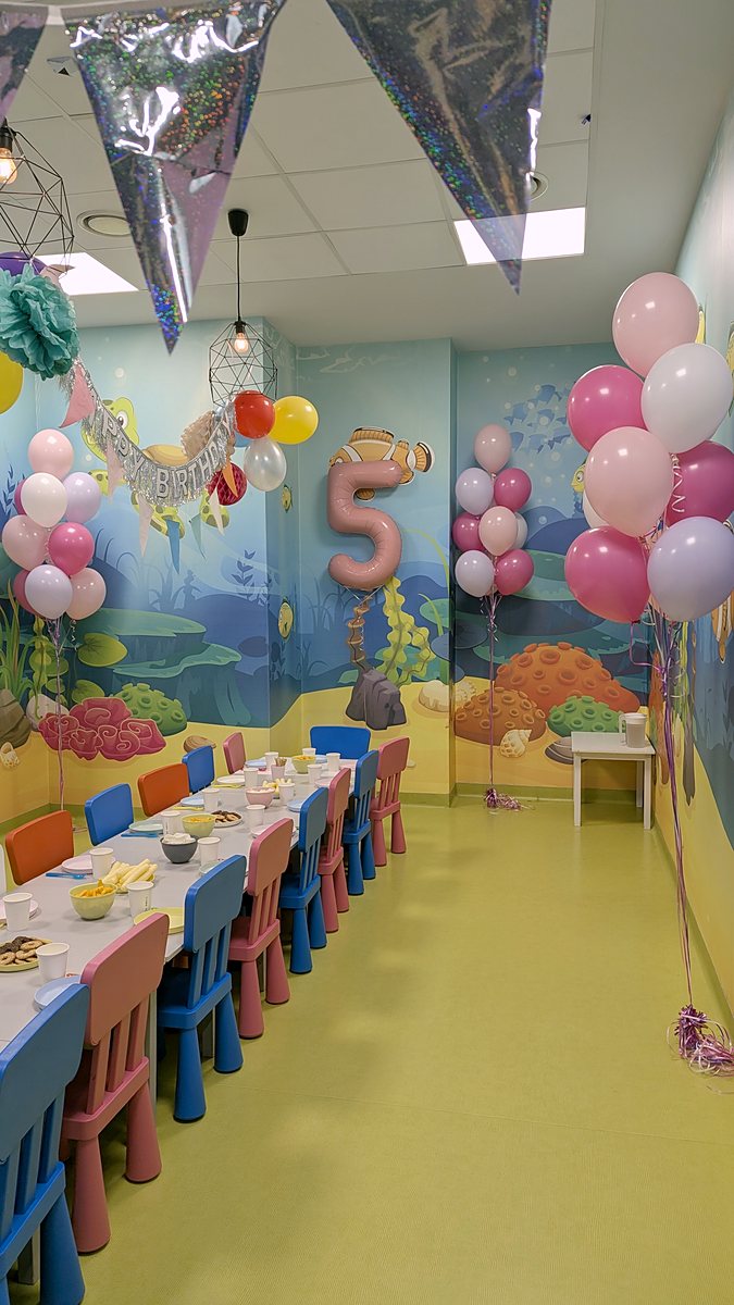 Sala zabaw z podwodnymi malowidłami udekorowana na 5. urodziny: foliowa cyfra 5 w pudrowym różu i bukiety balonów z helem w różu, fuksji i bieli
