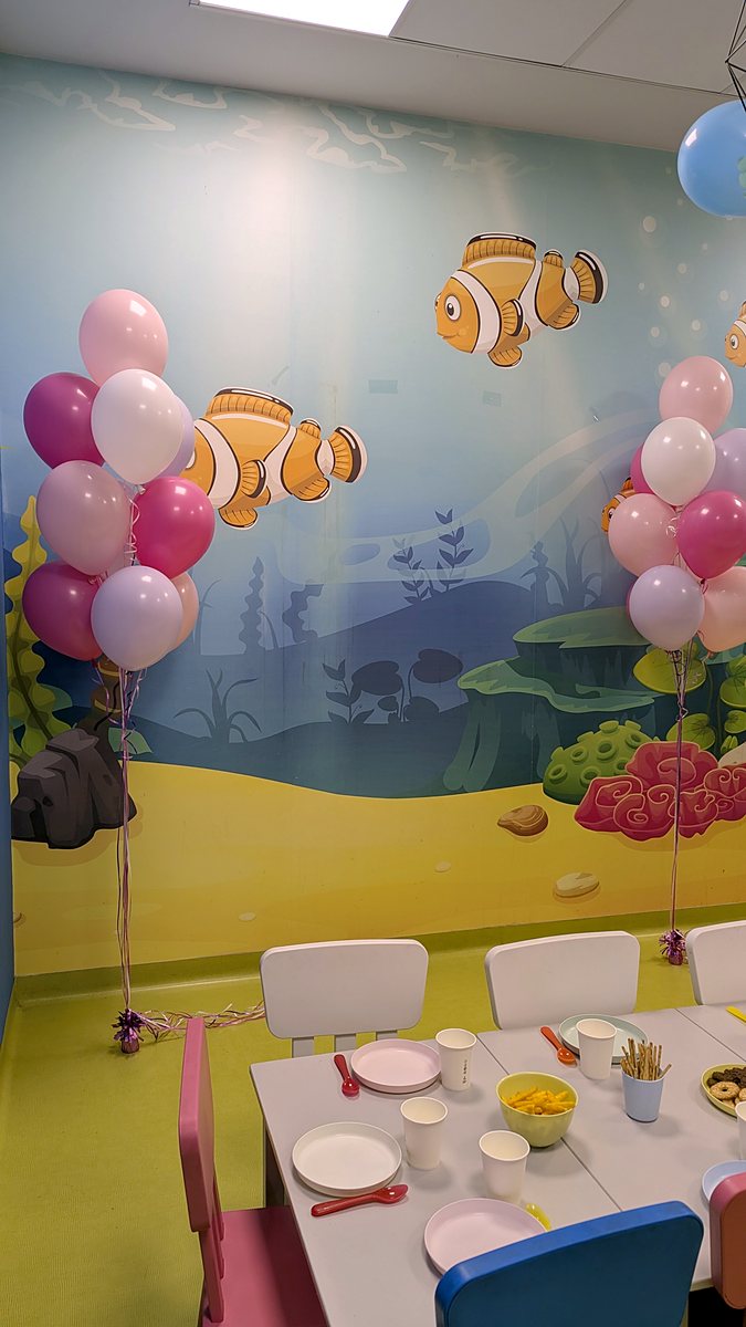 Dwa bukiety balonów z helem w różu, fuksji i bieli na tle ściany z rybkami