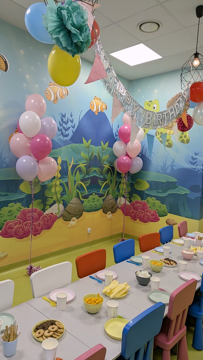 Bukiety balonów z helem nad stołem urodzinowym i kolorowe balony przy lampach